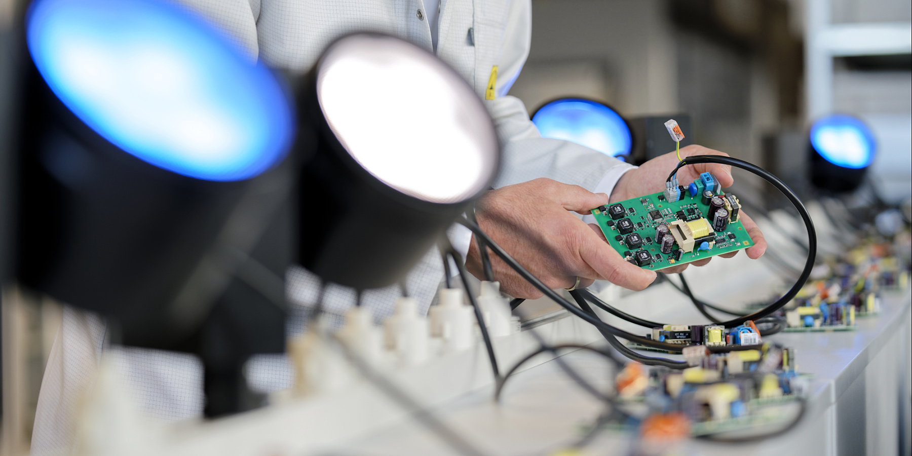 ERCO employee inspecting a circuit board under LED lights, quality assurance.