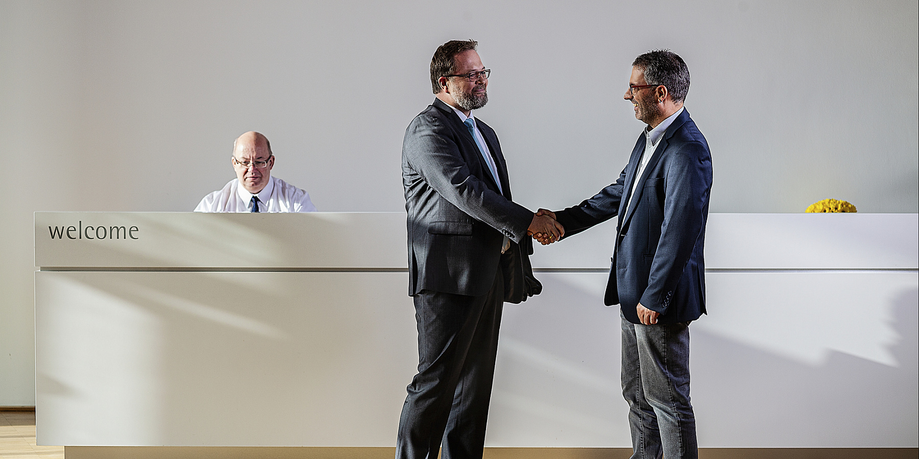 ERCO partners shaking hands in a modern reception area, symbolizing collaboration.