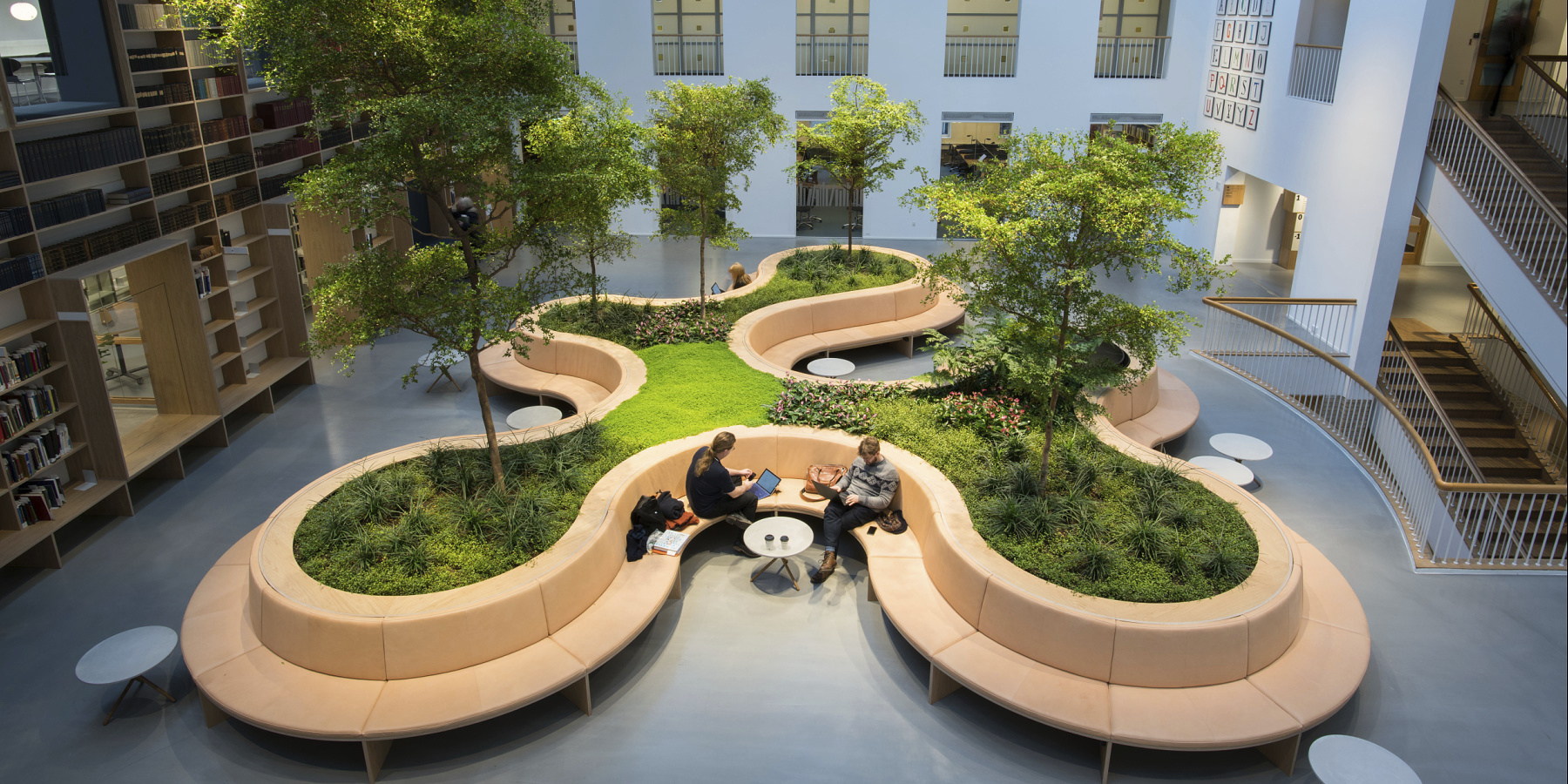 Indoor atrium with seating and trees, creating an inviting and biophilic atmosphere.