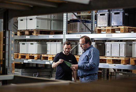ERCO employees inspect a component in the warehouse, ensuring quality for architectural lighting.