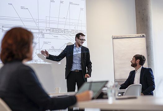 ERCO employee presenting a blueprint, showcasing lighting design in an architects office.