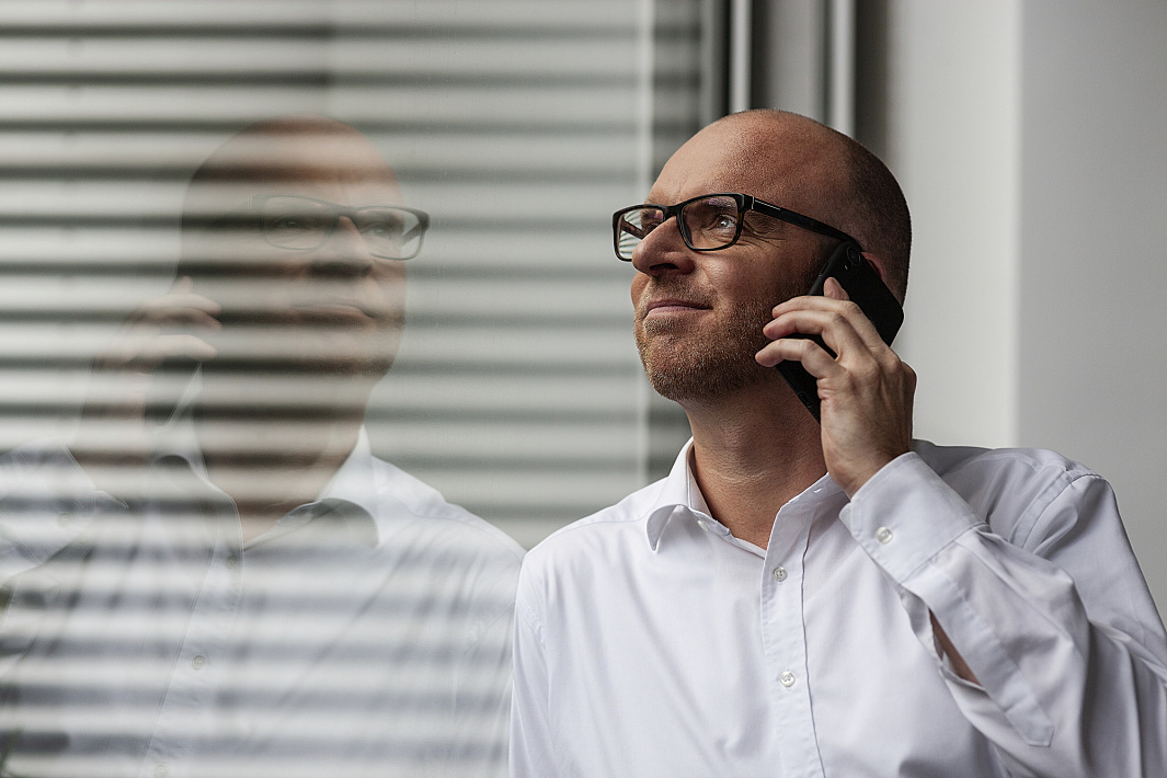 Man on phone, reflected in window. ERCO partner for successful collaboration.