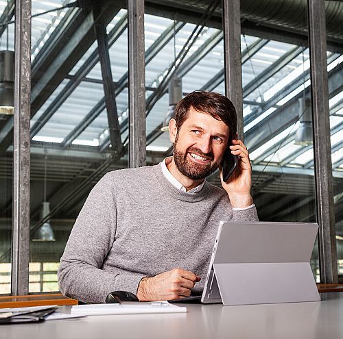 Man on phone with laptop at desk in office. ERCO partner.