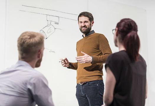 ERCO employee presenting a lighting design sketch, demonstrating ERCOs commitment to knowledge transfer and career growth.