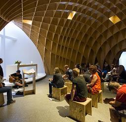 Church interior with wooden structure and ERCO lighting creating a contemplative atmosphere.