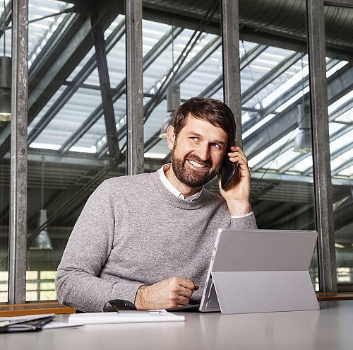 Man on phone at desk with laptop, in context of ERCOs social responsibility.