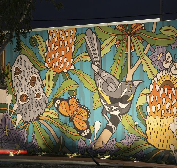 Illuminated outdoor art: Mural featuring Banksia, bird, and butterflies, accented with ERCO lighting.
