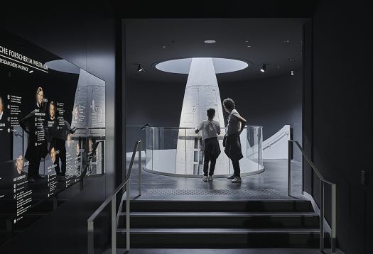 Visitors view a rocket at Deutsches Museum, illuminated by ERCO LED spotlights for a uniform lighting concept.