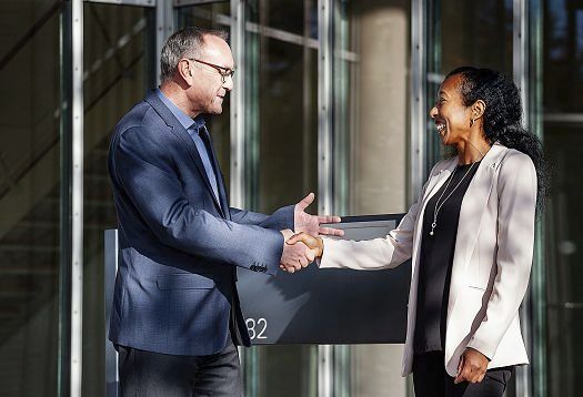 ERCO lighting consultants shaking hands in front of a building, representing lighting design consultation.