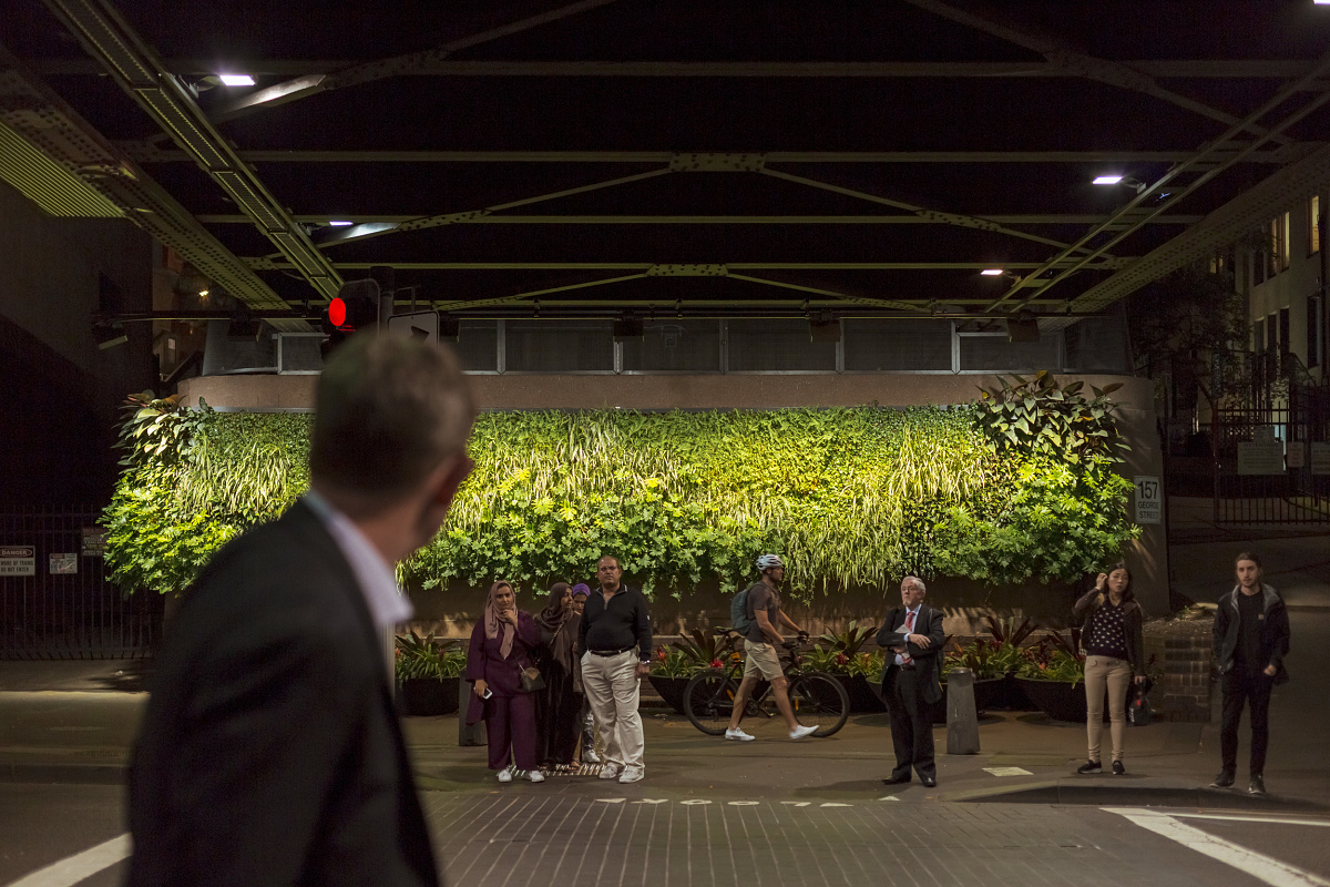 Illuminated green wall in the city, enhancing well-being. ERCO lighting design for sustainable interiors.