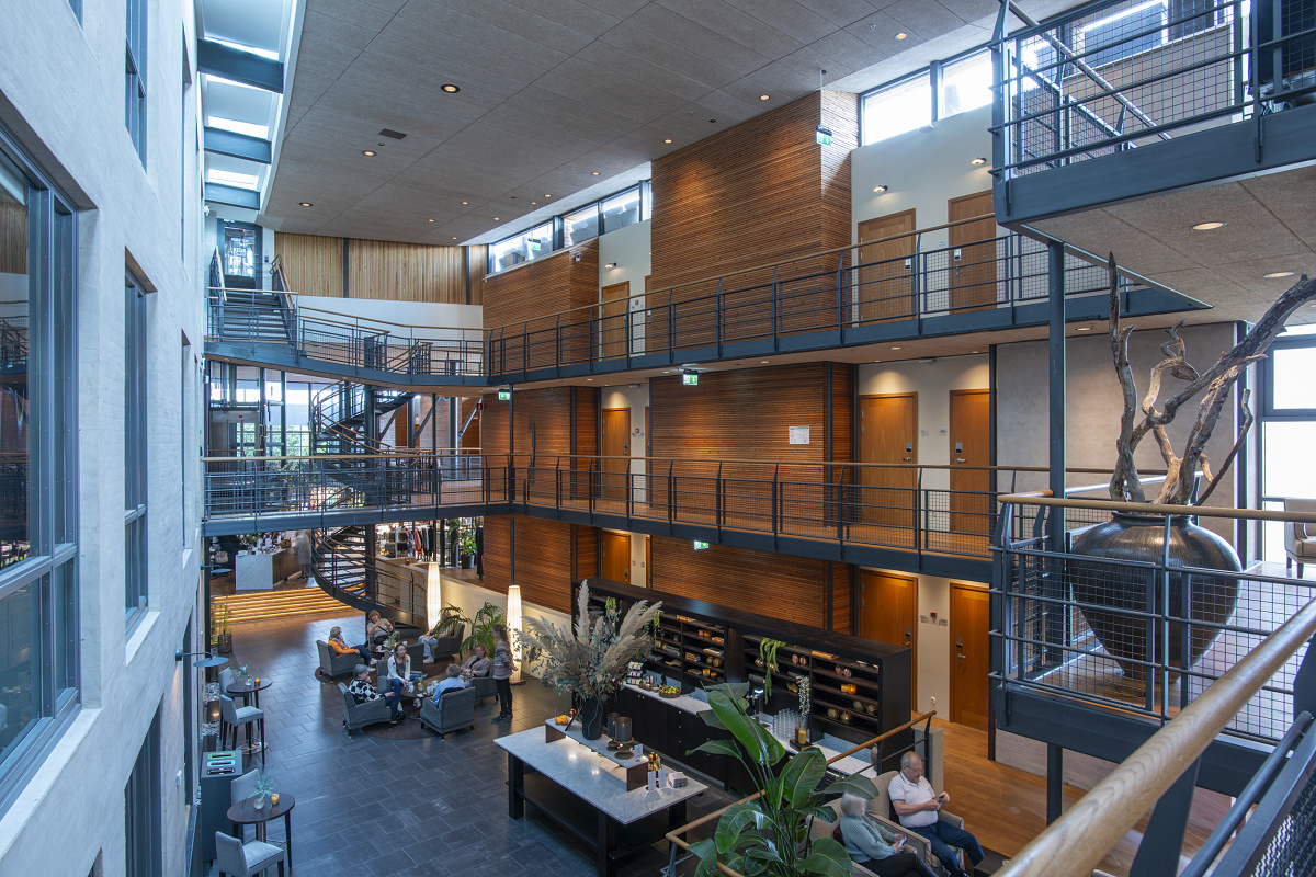 Hotel Skansen, Båstad: Multi-story lobby featuring ERCO lighting for visual comfort.