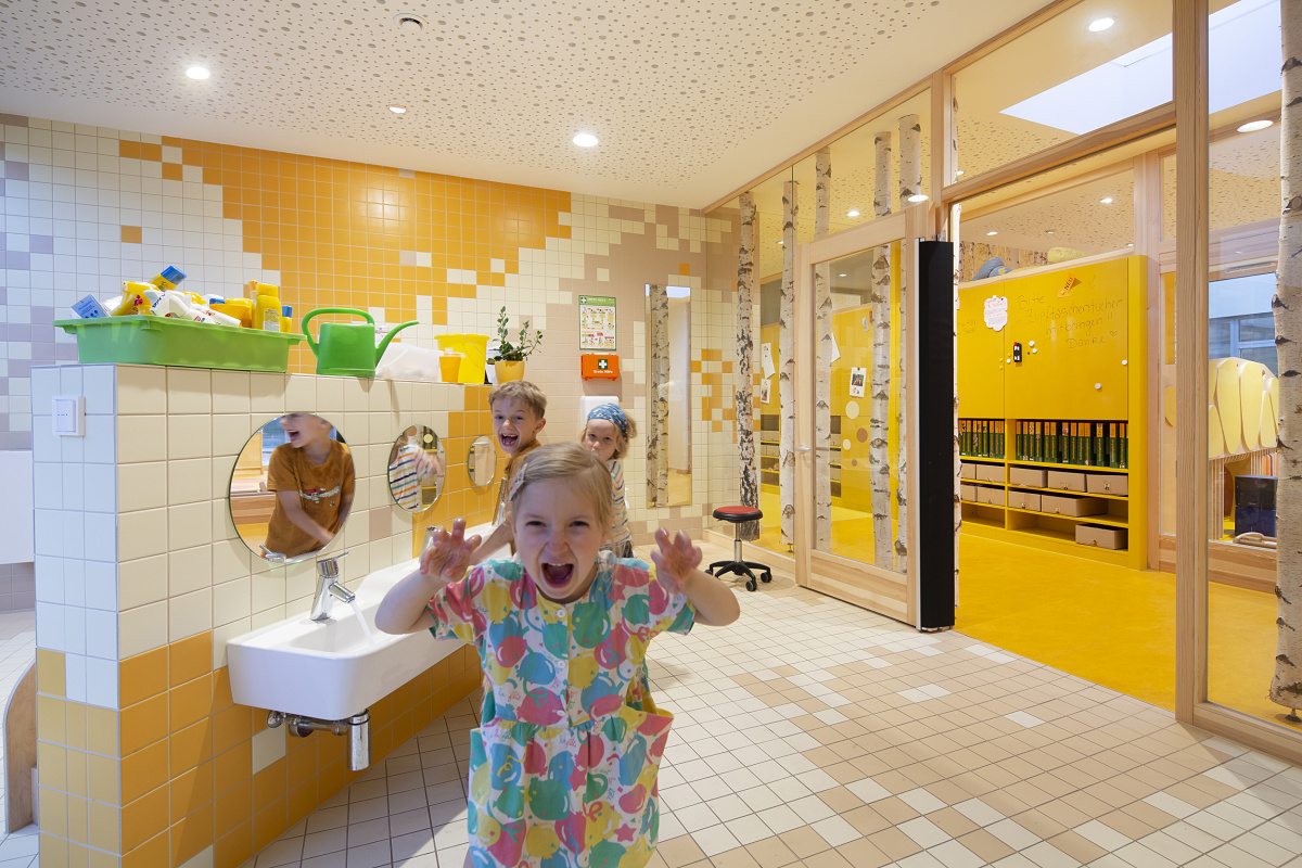 Children play in the bright washroom of Rappelkiste Day Care, lit by ERCO LED lighting.