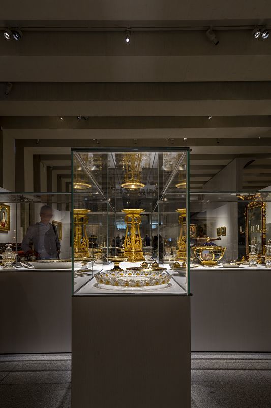 Illuminated display case with golden artifacts in the Galería de las Colecciones Reales, Madrid.