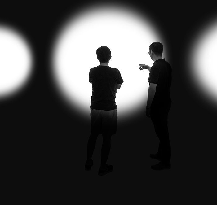 Two people discussing ERCO outdoor lighting illuminating a public space at night.