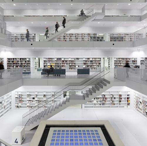 Bright library with staircases and bookshelves, illuminated by ERCO outdoor luminaires for robust indoor lighting.