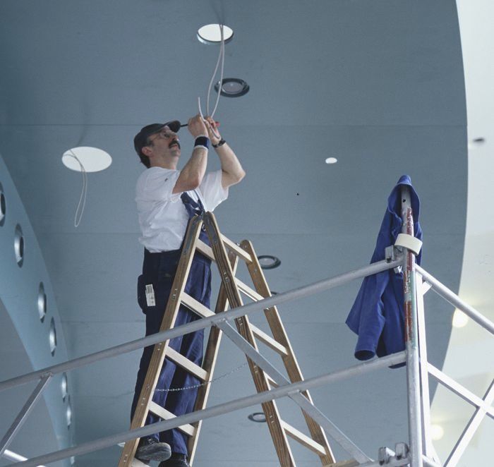 Electrician on ladder installing Lightcast LED recessed ceiling luminaires for modernization.
