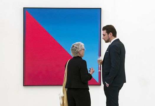 Gallery visitors view abstract art illuminated by ERCO lighting.