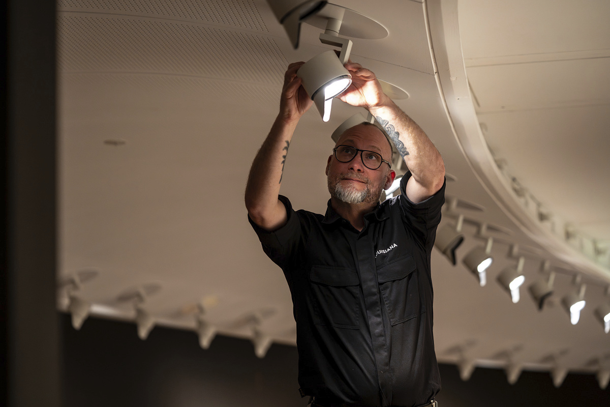 A man adjusts an ERCO Parscan LED spotlight at the Louisiana Museum, optimizing exhibition lighting.
