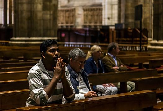 Worshippers in Milan Cathedral, illuminated by ERCO LED spotlights for energy efficiency.