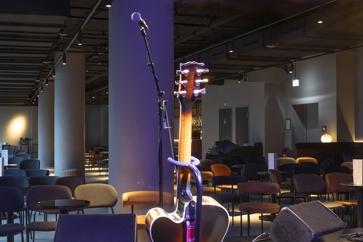 Acoustic guitar and microphone on stage at NICA Jazz Club, illuminated by ERCO spotlights.