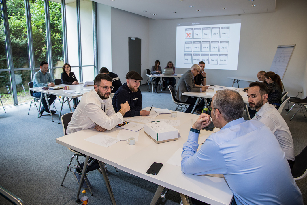 ERCO sales team meeting: Sales professionals discuss lighting solutions in a bright conference room.