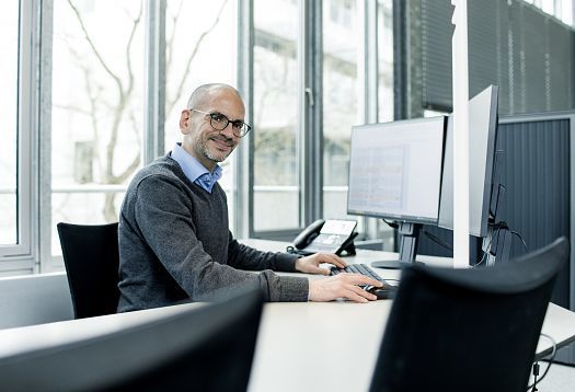 ERCO sales professional working at a computer in the office, focused on lighting design.