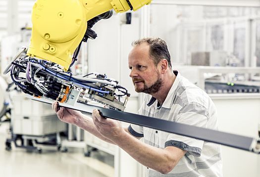ERCO employee working with a yellow industrial robot on product development.
