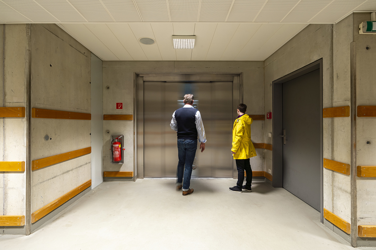People in front of an elevator in the Ferry Porsche Congress Center, illuminated by energy-efficient ERCO LED downlights.