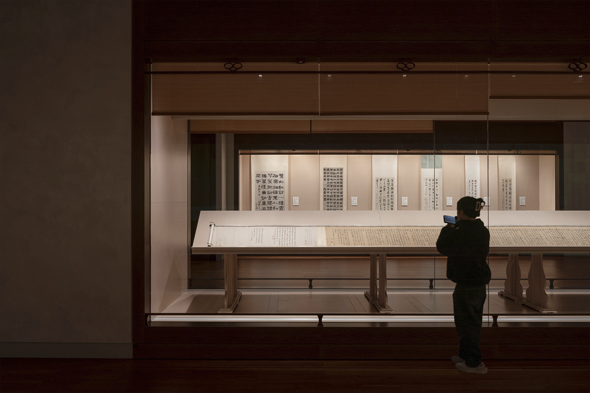 Visitor at Shanghai Museum East views calligraphy, illuminated by ERCO spotlights for optimal preservation.