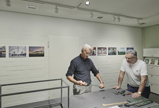 USM Show Office: Two people assemble USM furniture under ERCO track downlights for flexible office lighting.