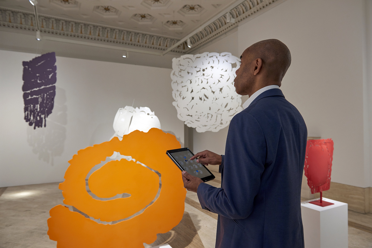 Man controls ERCO Casambi luminaires with Bluetooth via tablet in a gallery.