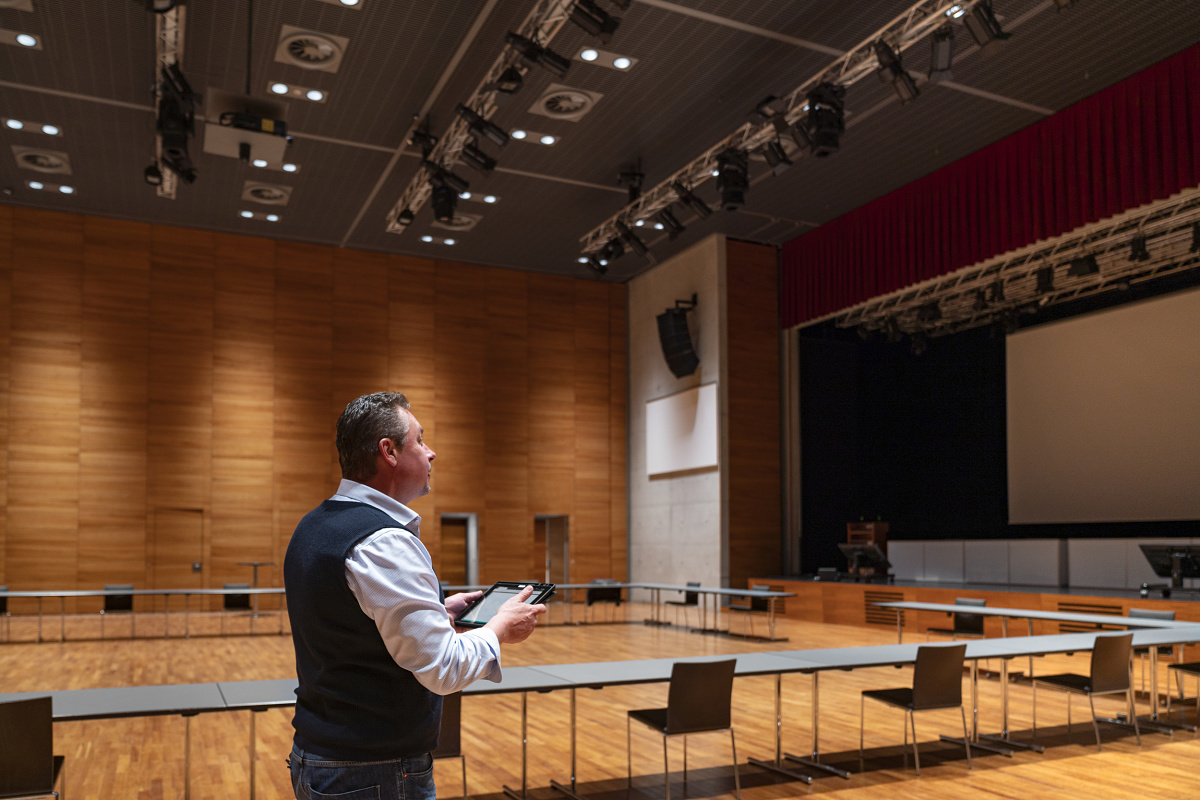 Man controls ERCO Casambi luminaires with Bluetooth in a conference room.