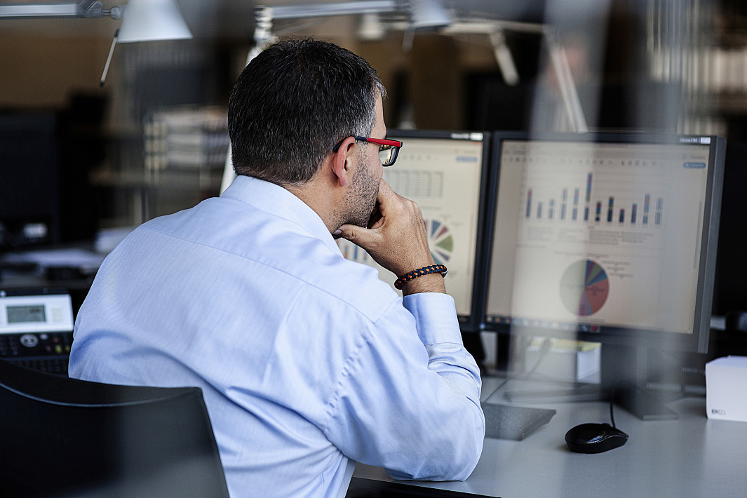 A man analyzes data on dual monitors in an office setting.