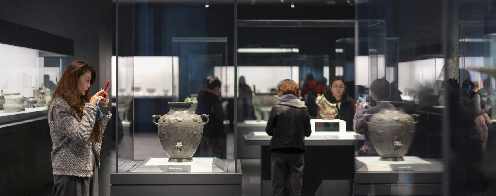 Visitors view illuminated bronze artifacts at Shanghai Museum East, displayed with ERCO spotlights.